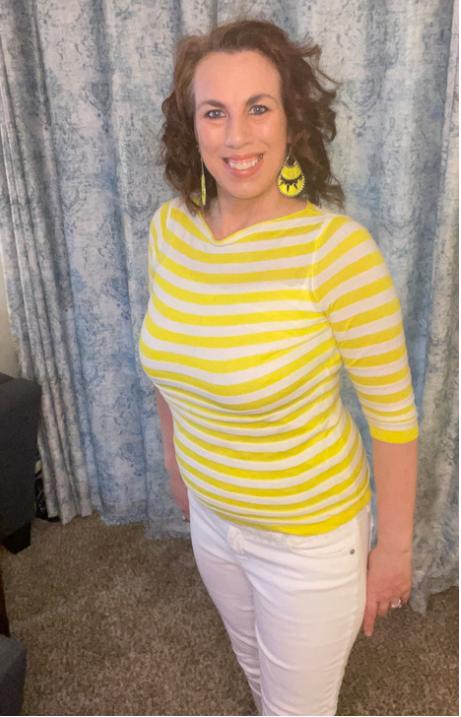 A woman is wearing a yellow and white striped shirt and white pants.