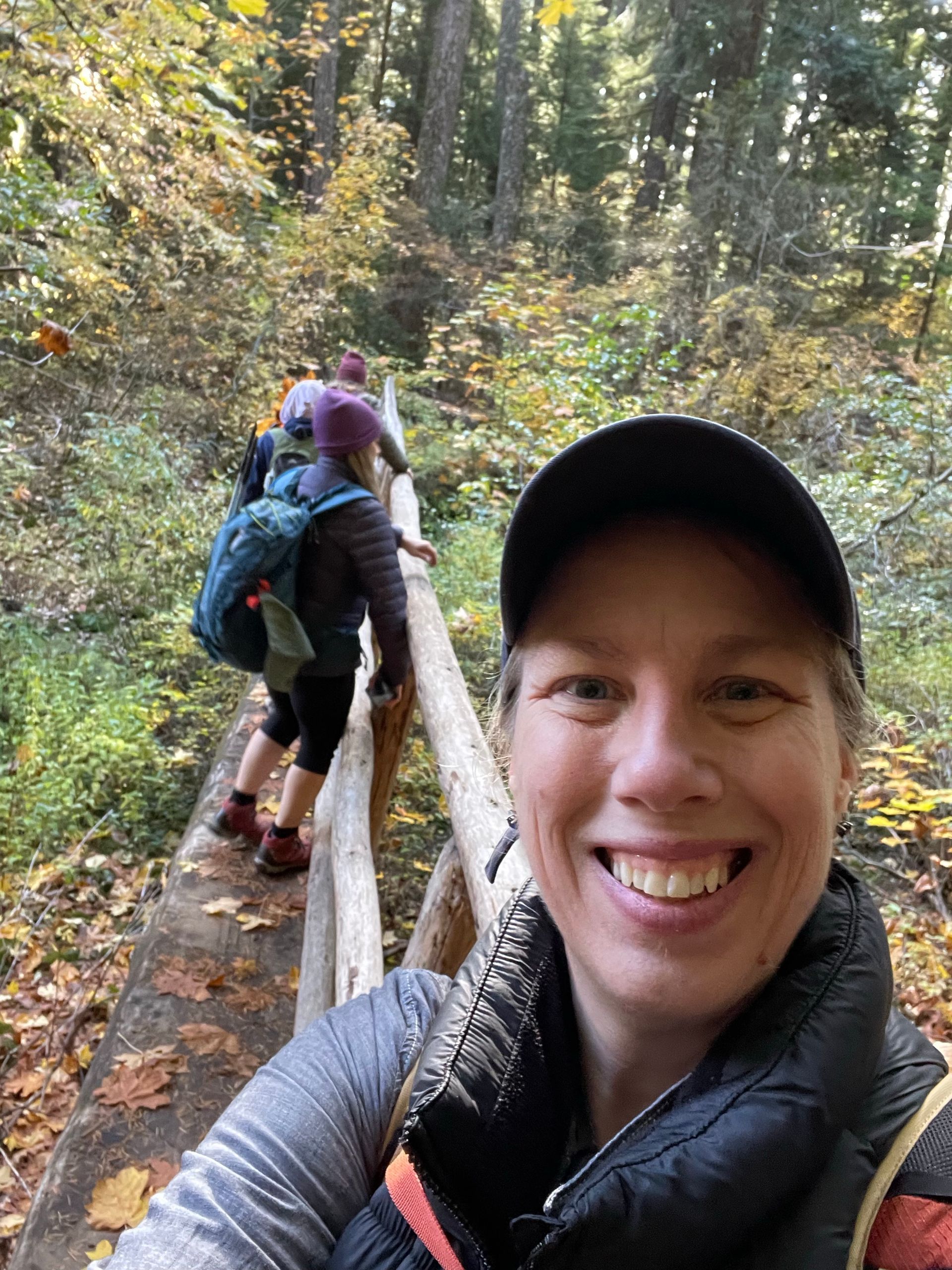Angela is taking a selfie while hiking in the woods.