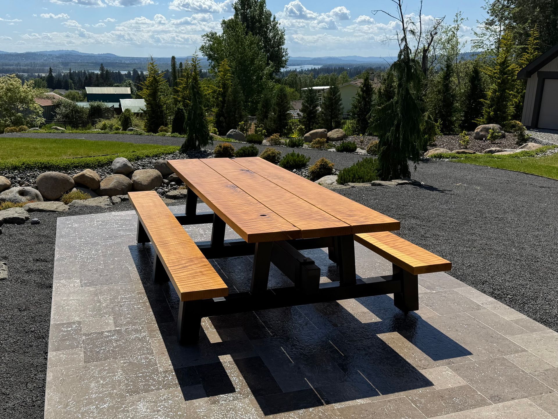 Custom outdoor dining table with benches overlooking a scenic Pacific Northwest view.