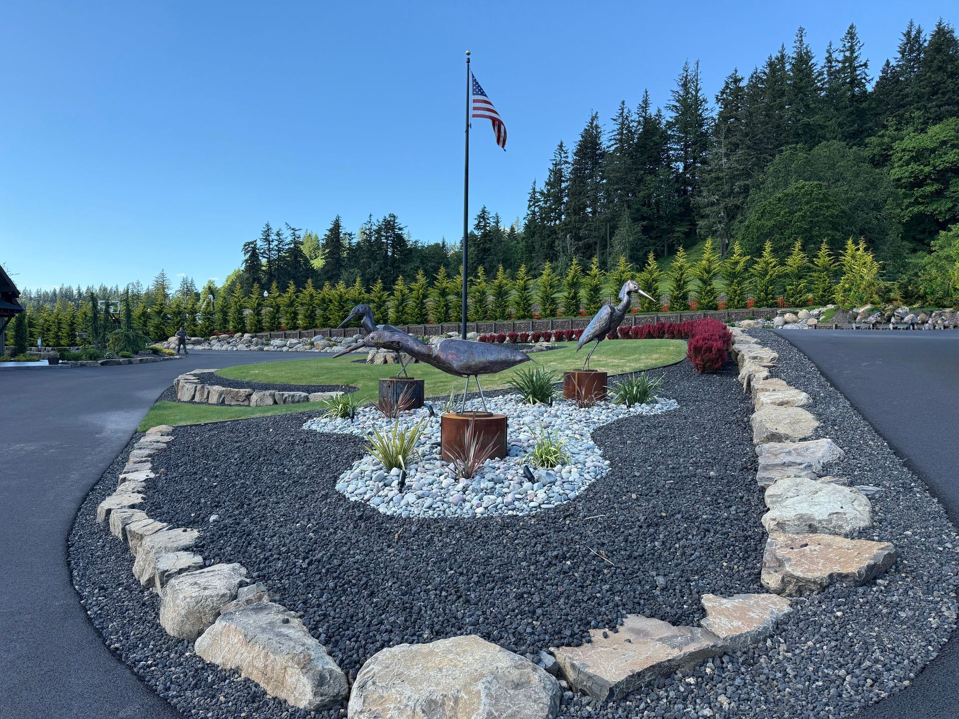 Custom landscape design with decorative metal bird sculptures and stone border.