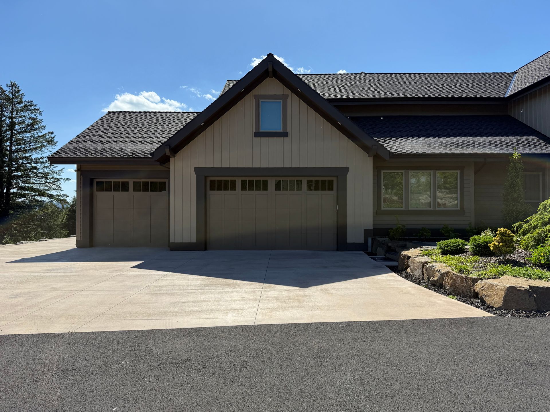 Luxury custom home garage exterior with stone landscaping and dark trim details.