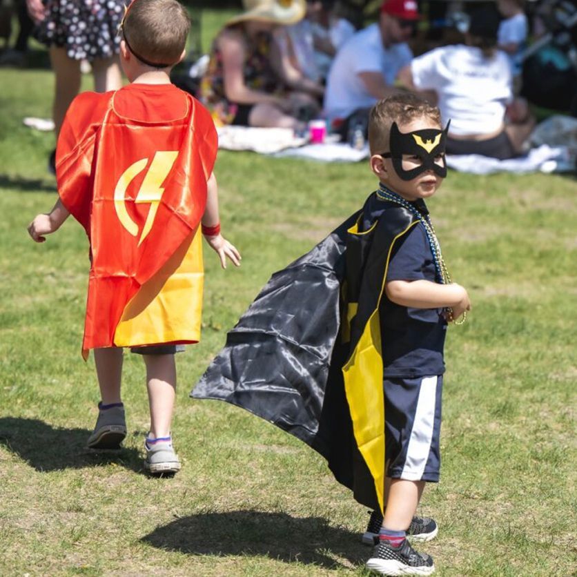 A little boy wearing Batman superhero gear runs around the park at last year's Walk