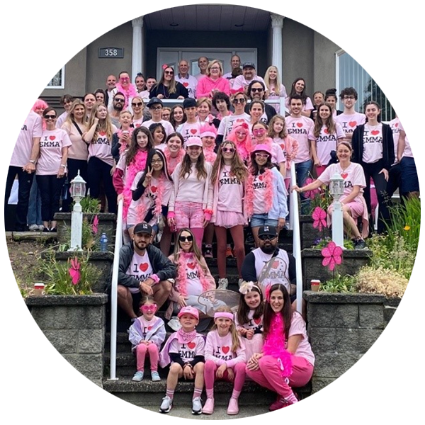 La grande équipe d'Emma, tous vêtus de t-shirts roses assortis, posant devant la maison. 