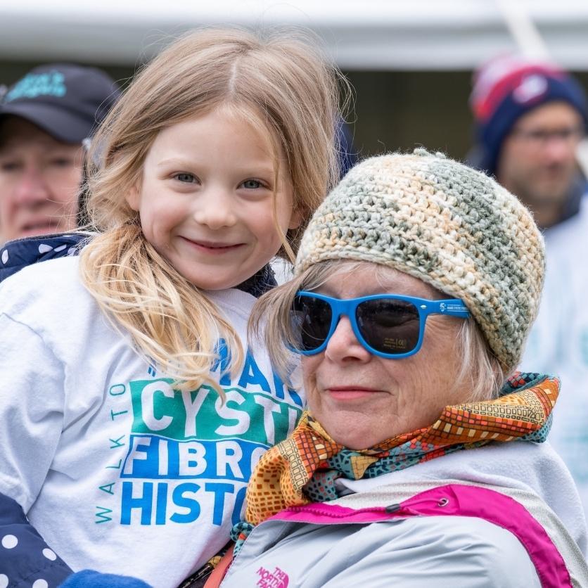 An older woman and her granddaughter wearing Walk tees smile for the camera
