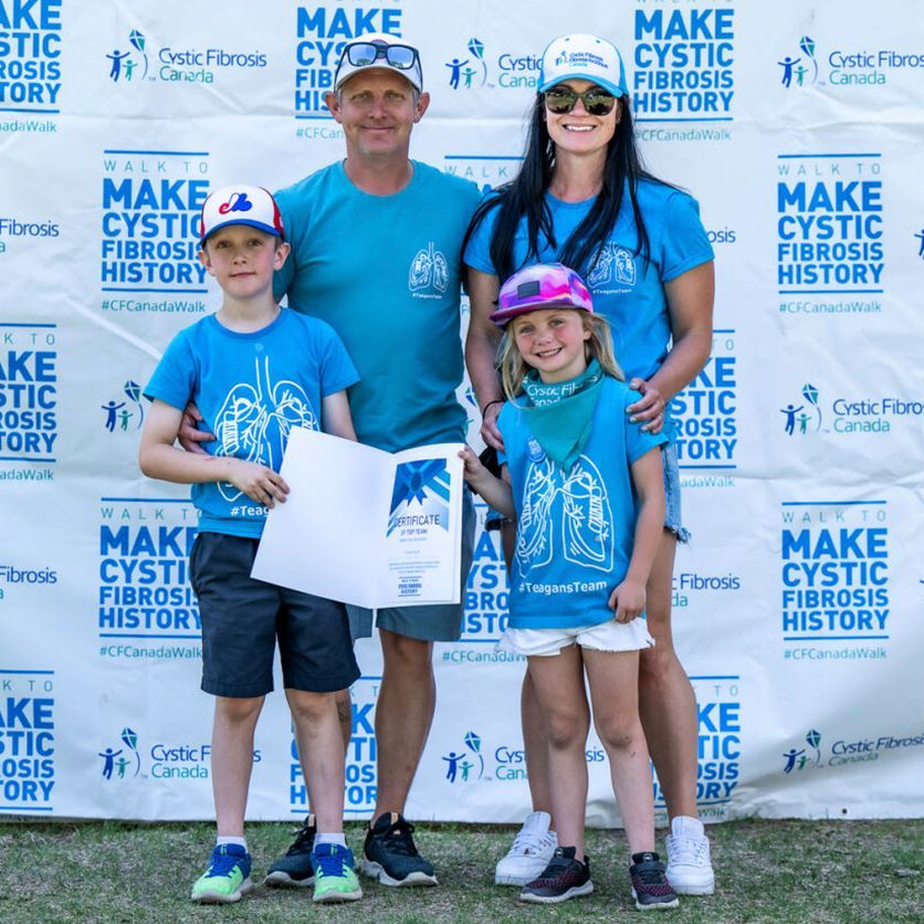 Two adults and two children wearing Walk gear hold up an award against the a Walk banner background