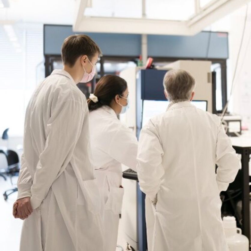 Three researchers look at results in a hospital lab