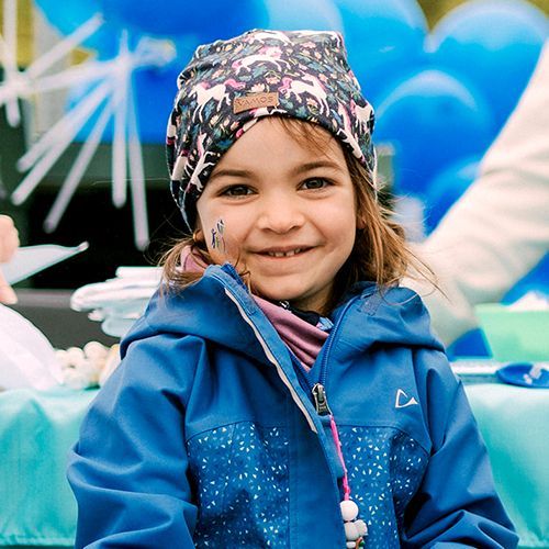 Young girl at The Walk wearing a flowered cap and blue jacket.