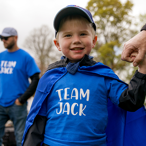 A Walk Jr participant, wearing a blue cape and a shirt that says, Team Jack.