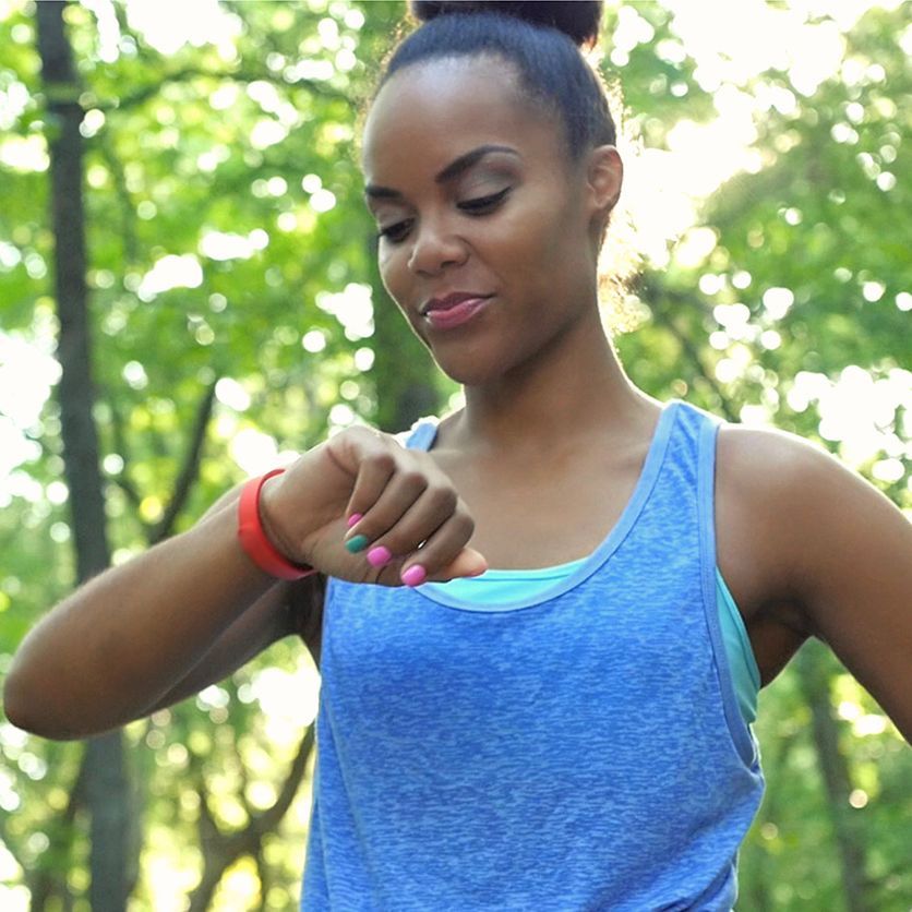 An African American woman looks at her smart watch to track her fitness