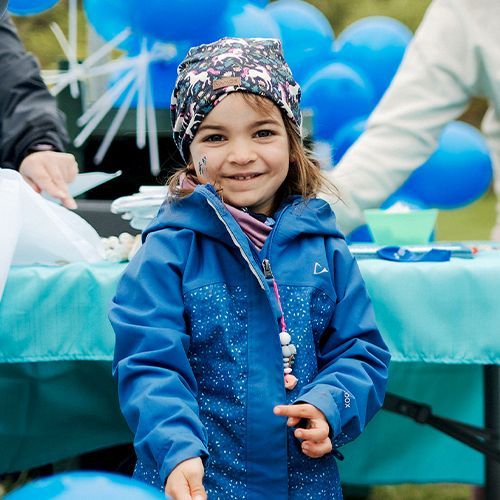 Jeune fille au Walk portant une casquette fleurie et une veste bleue.