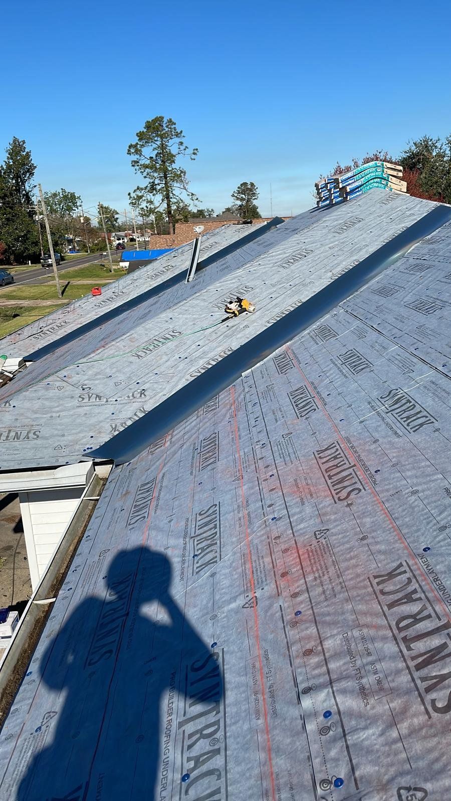Rooftop with black underlayment; construction in progress on a sunny day.