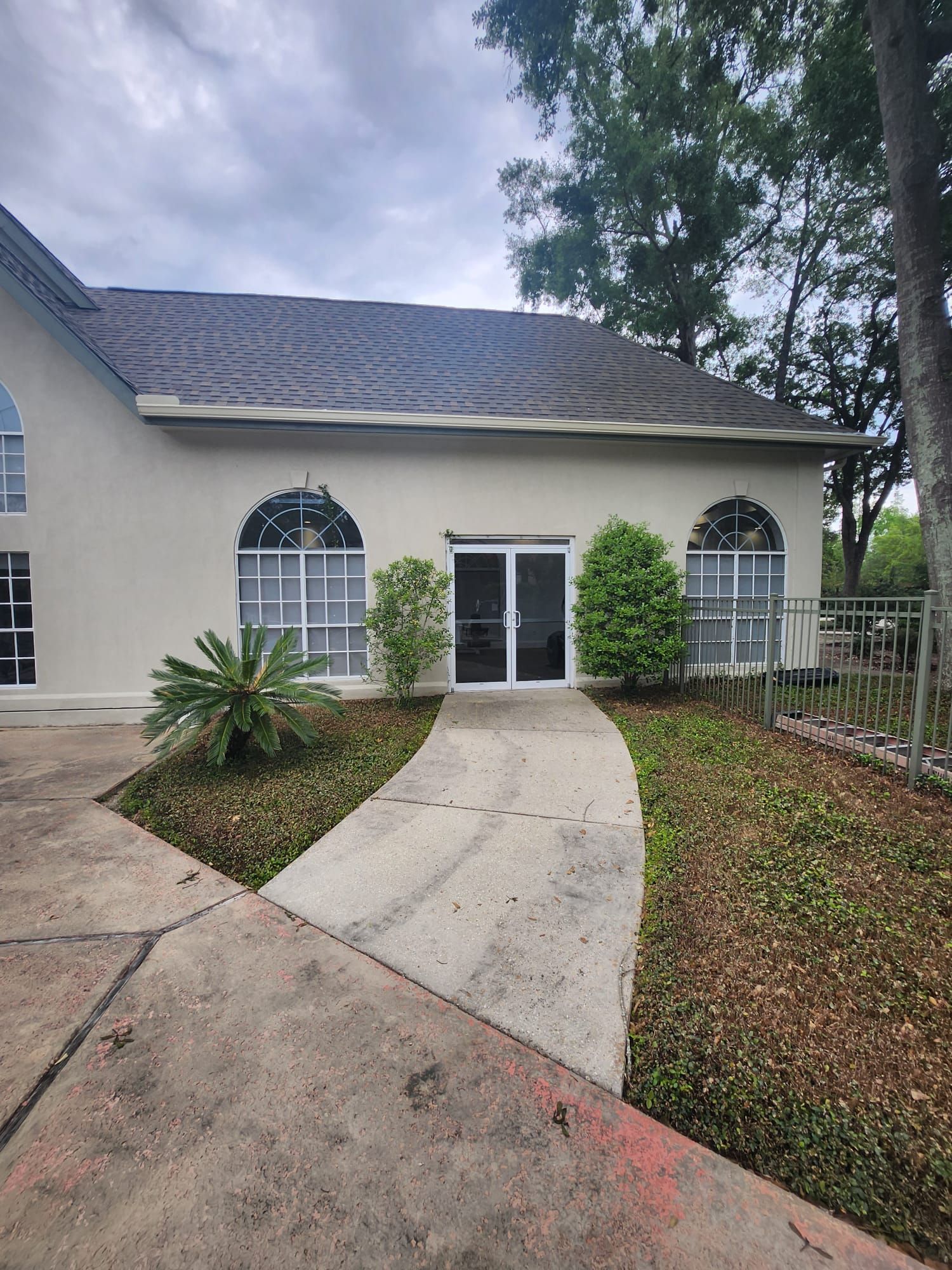 A building with arched windows and a walkway leading to a double door entrance.