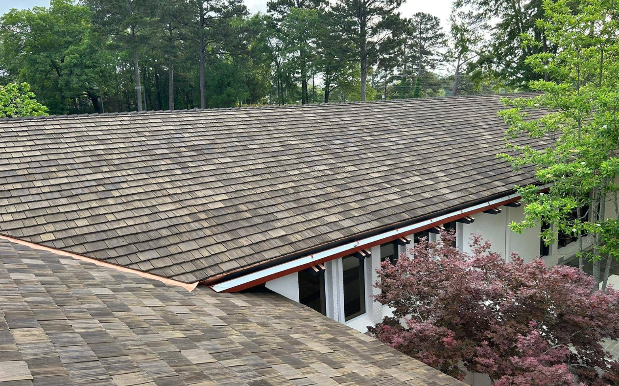 Wood shake roof of a building, surrounded by trees and foliage.