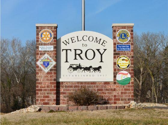 Welcome sign for Troy, brick structure, with city name and logos for service clubs.