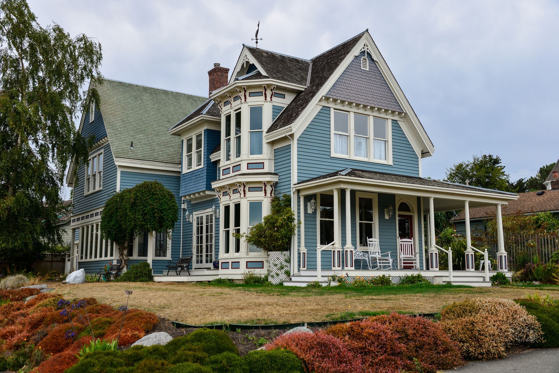 Blue Victorian house with white trim, porch, and a well-manicured lawn. Blue Victorian house with white trim, porch, and a well-manicured lawn.