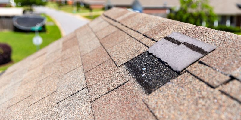 Roof shingles with missing and damaged sections, focusing on repair.