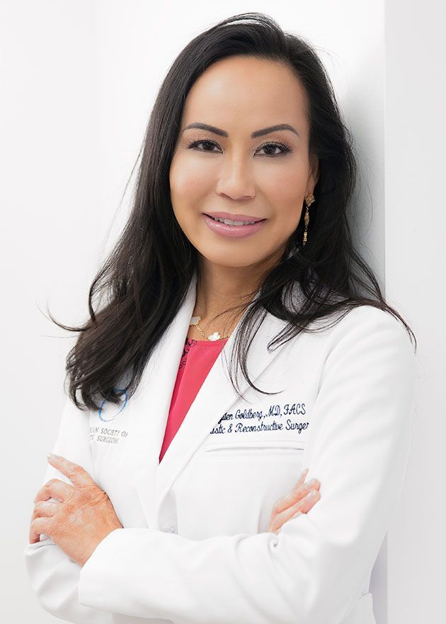 A woman in a white lab coat is standing with her arms crossed.