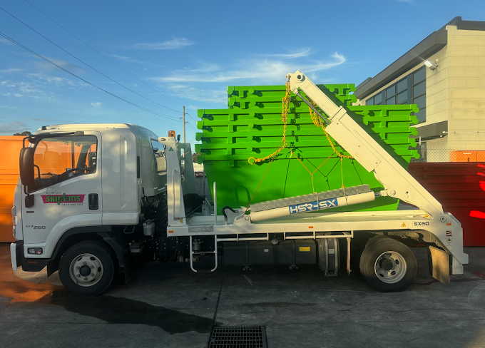White Flatbed Truck Carrying Multiple Green Skip Bins Stacked Upon Each Other — Kempsey Skip Bins In Gladstone, QLD