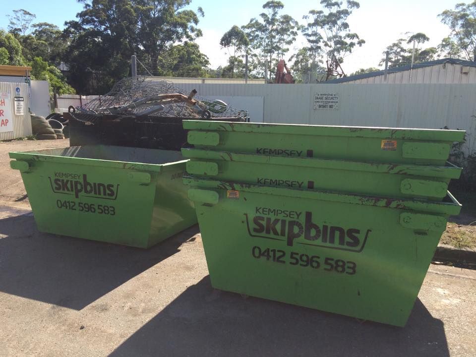 Two Green Skip Bins Sitting In Front Of A Retaining Wall — Kempsey Skip Bins In Smithtown, NSW