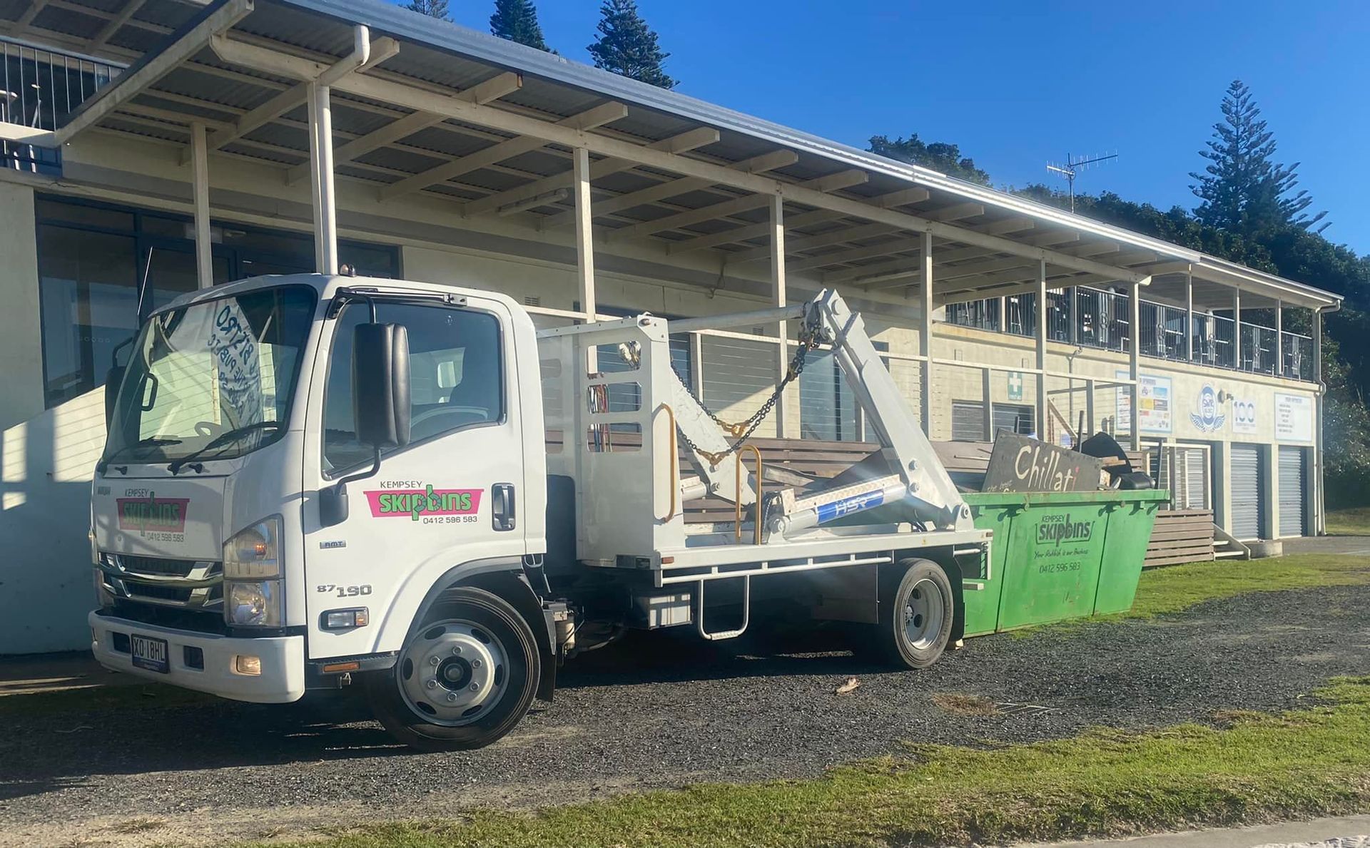 A Green Skip Bin Sitting Behind A White Flatbed Truck — Kempsey Skip Bins In Smithtown, NSW