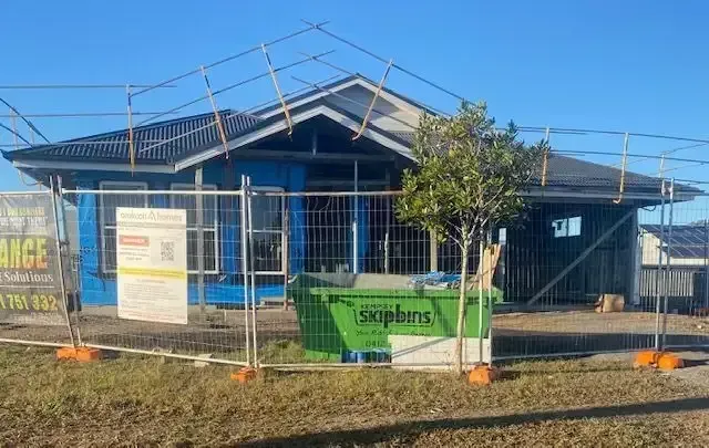 House Under Construction Behind a Safety Fence; a Green Skip Bin in Front — Kempsey Skip Bins In South West Rocks, NSW