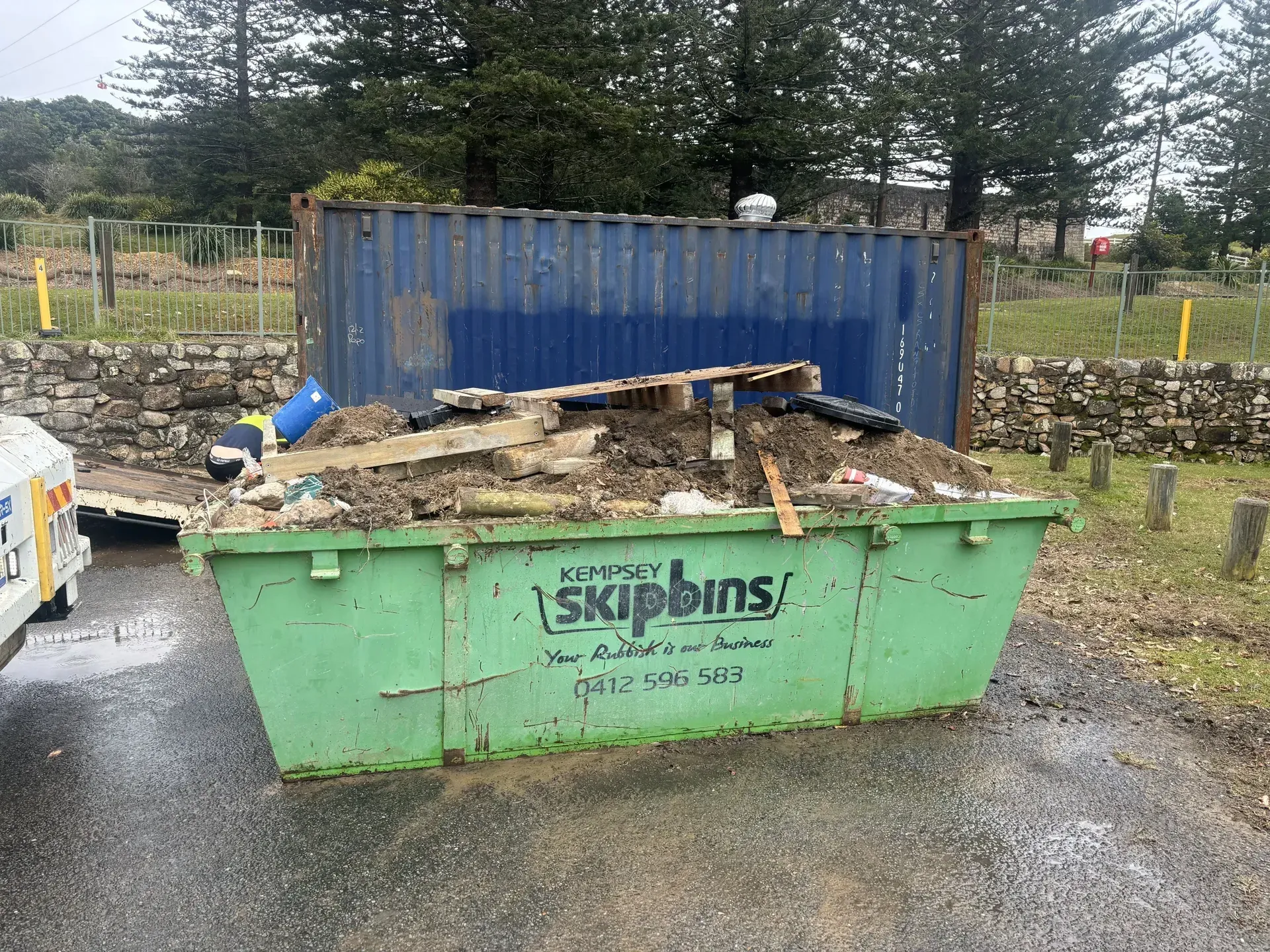 Green Skip Bin Overflowing With Debris, Parked on Asphalt — Kempsey Skip Bins In Frederickton, NSW
