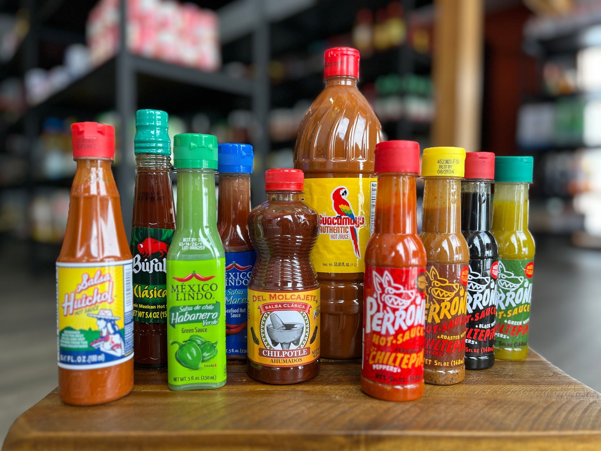 Several bottles of hot sauce are sitting on a wooden table.
