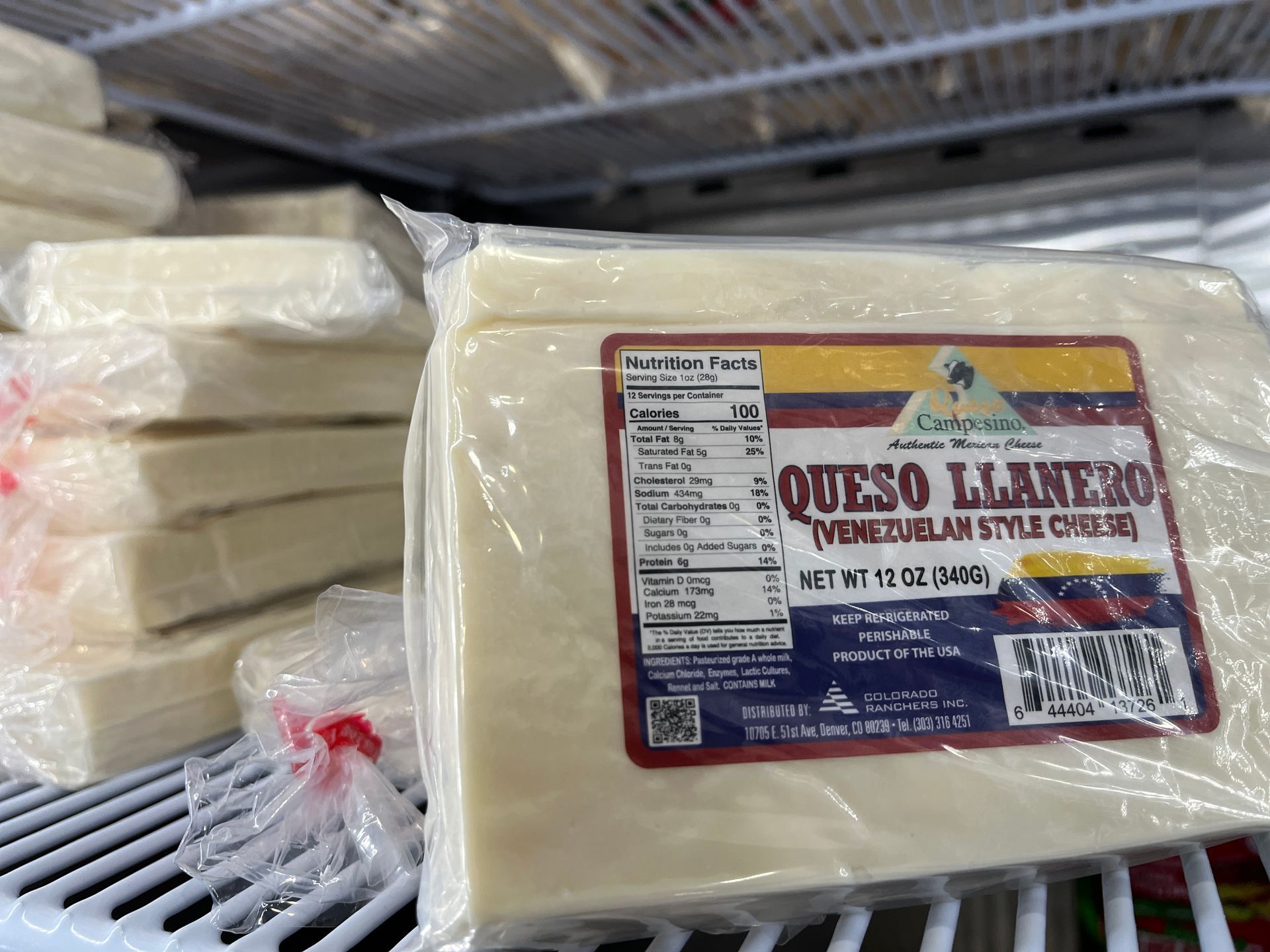 A block of queso llanero cheese is sitting on a shelf in a refrigerator.
