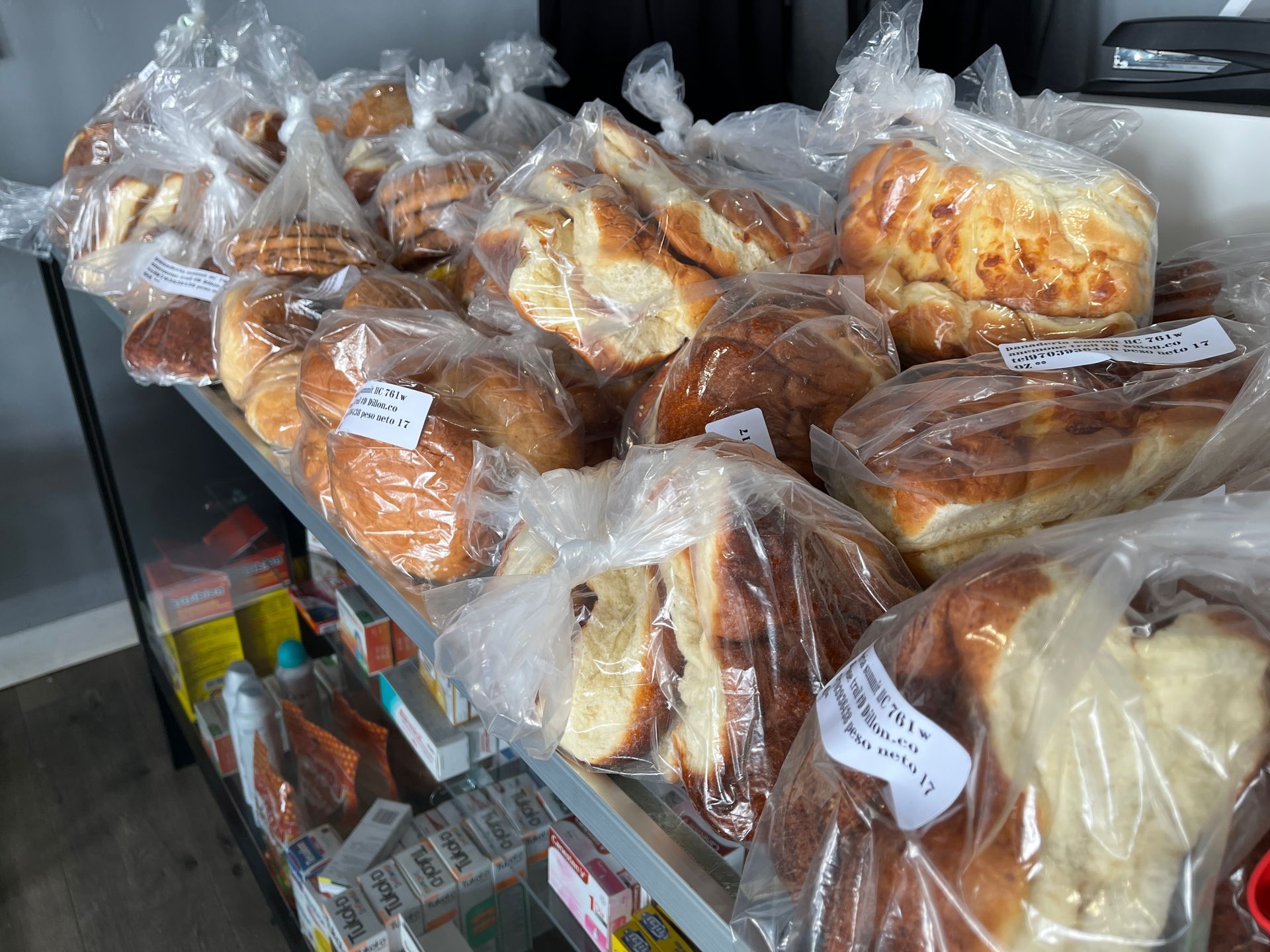 A bunch of bread is sitting on a shelf in plastic bags.