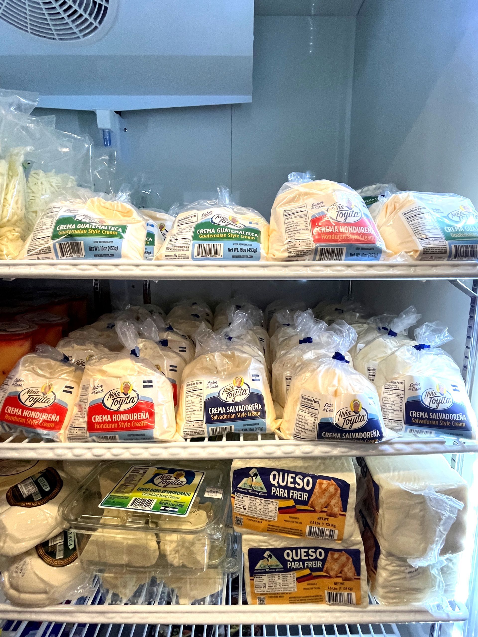 Refrigerator shelves filled with packaged cheese products.