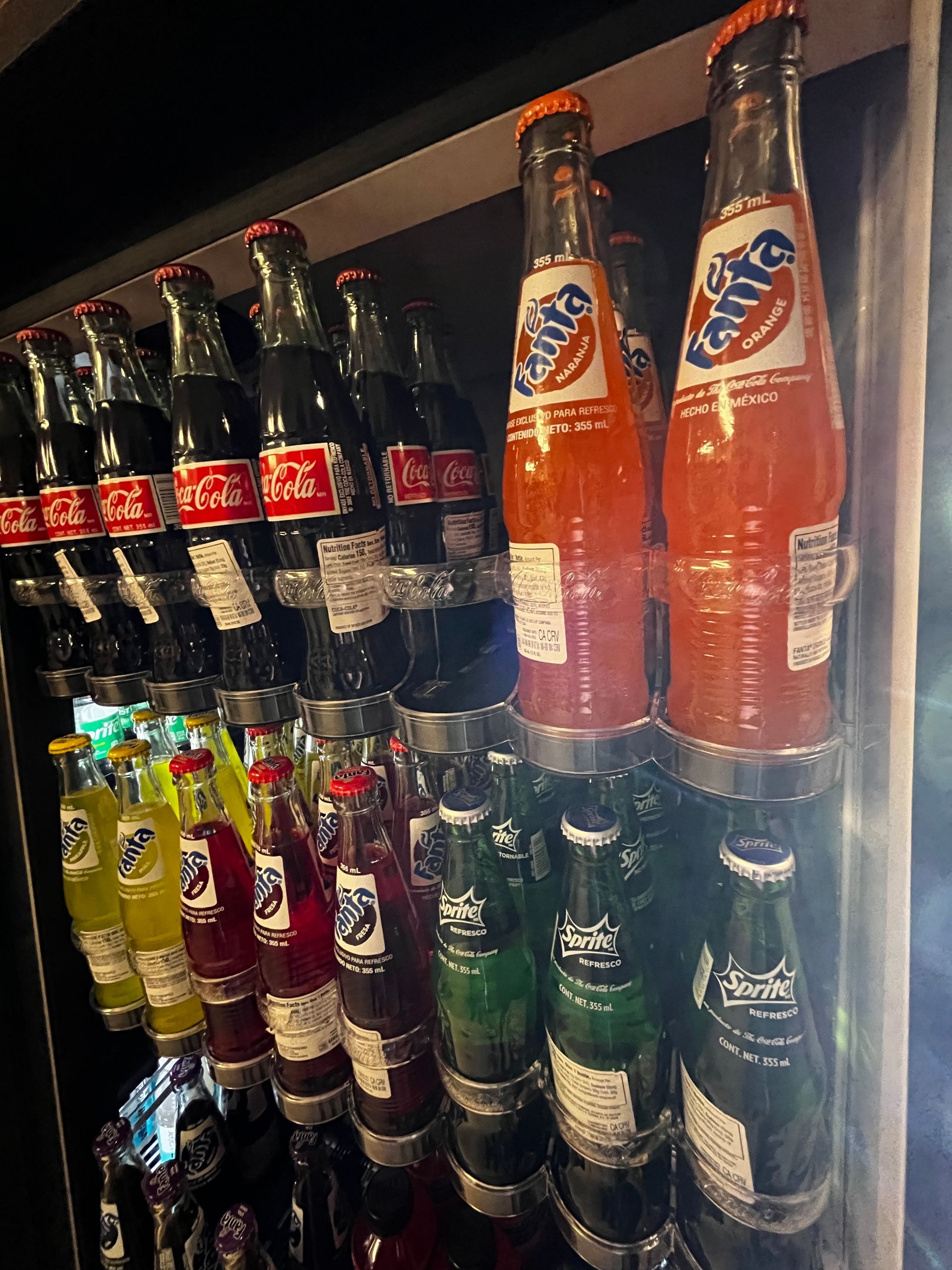 Several bottles of soda are stacked on top of each other on a shelf.