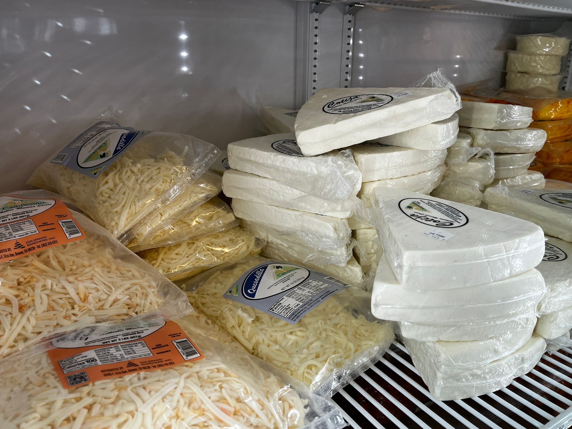 A refrigerator filled with bags of shredded cheese and sliced cheese.