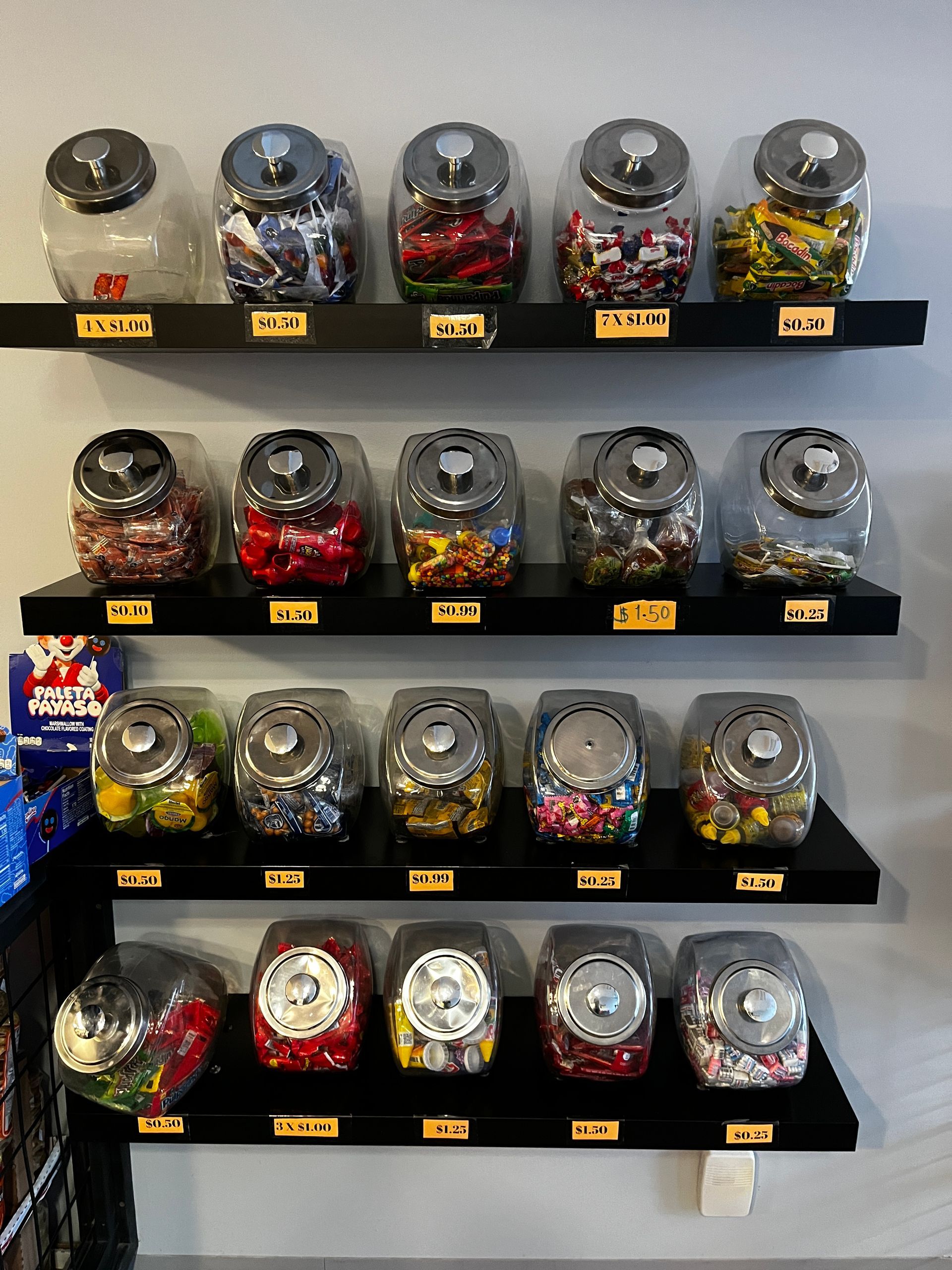 There are many jars of candy on the shelves.