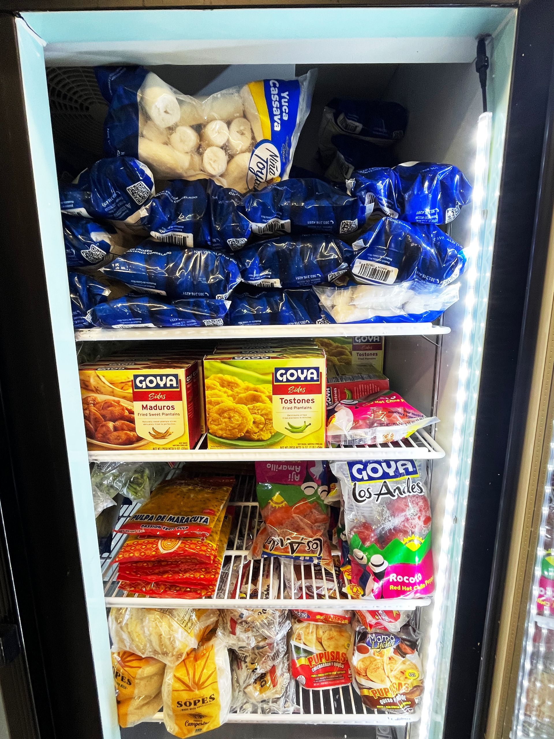 Freezer filled with various frozen food packages, mostly blue and colorful, inside a store.