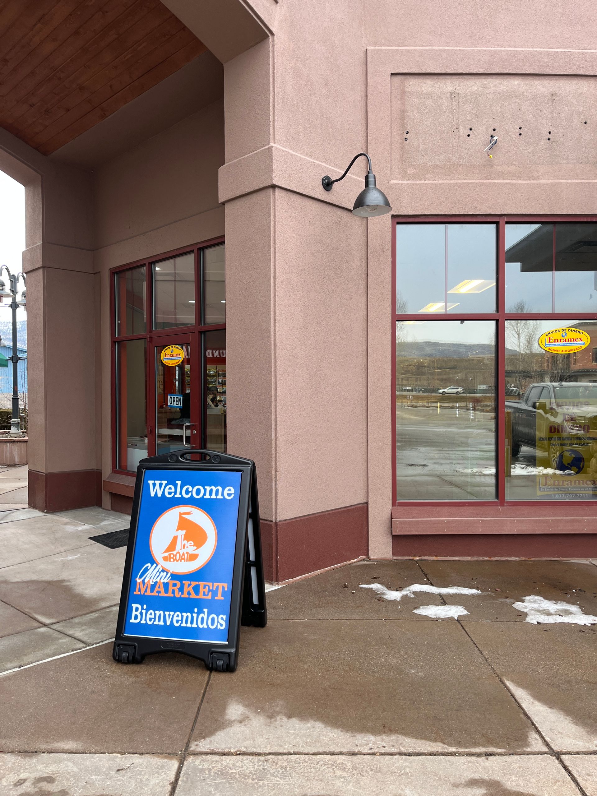 Exterior of a pet store with a welcome sign. Reddish-brown building, glass windows, and a black sidewalk sign.