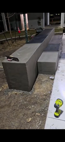 Concrete benches under construction. A trowel and drill sit nearby.