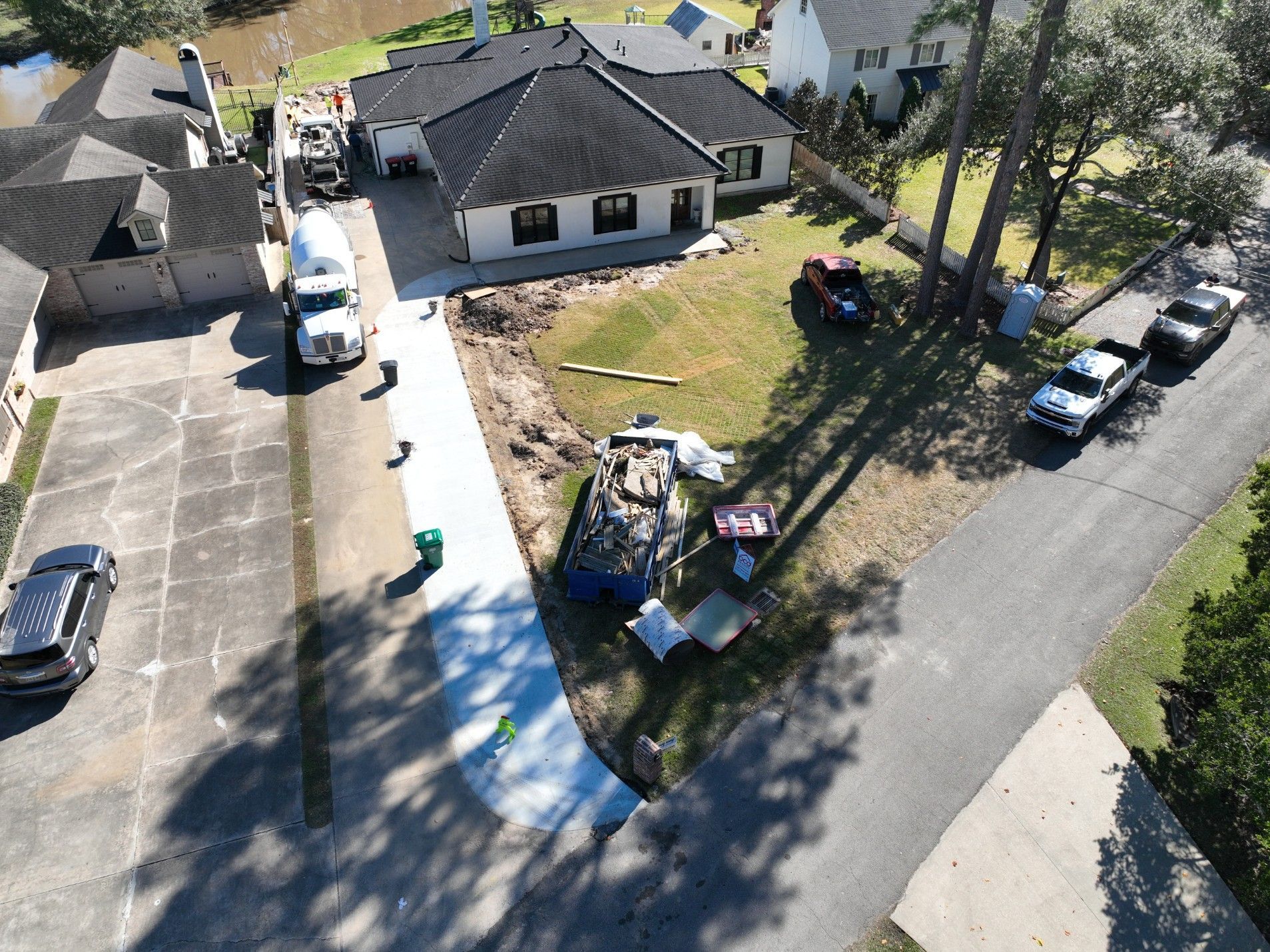 An aerial view shows a house under construction with parked trucks and construction materials.