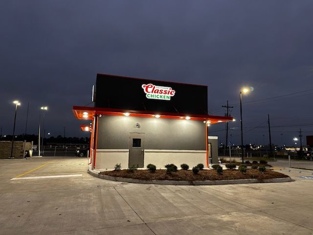 Classic Chicken restaurant exterior at dusk with orange and black accents and lit sign.