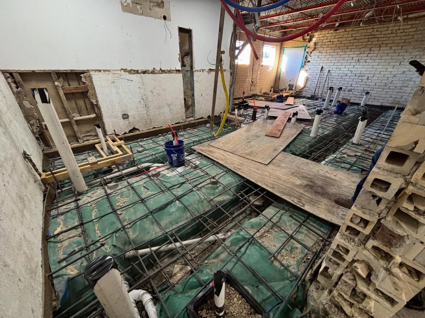 Bathroom renovation in progress, exposed plumbing and concrete reinforcement on the floor.