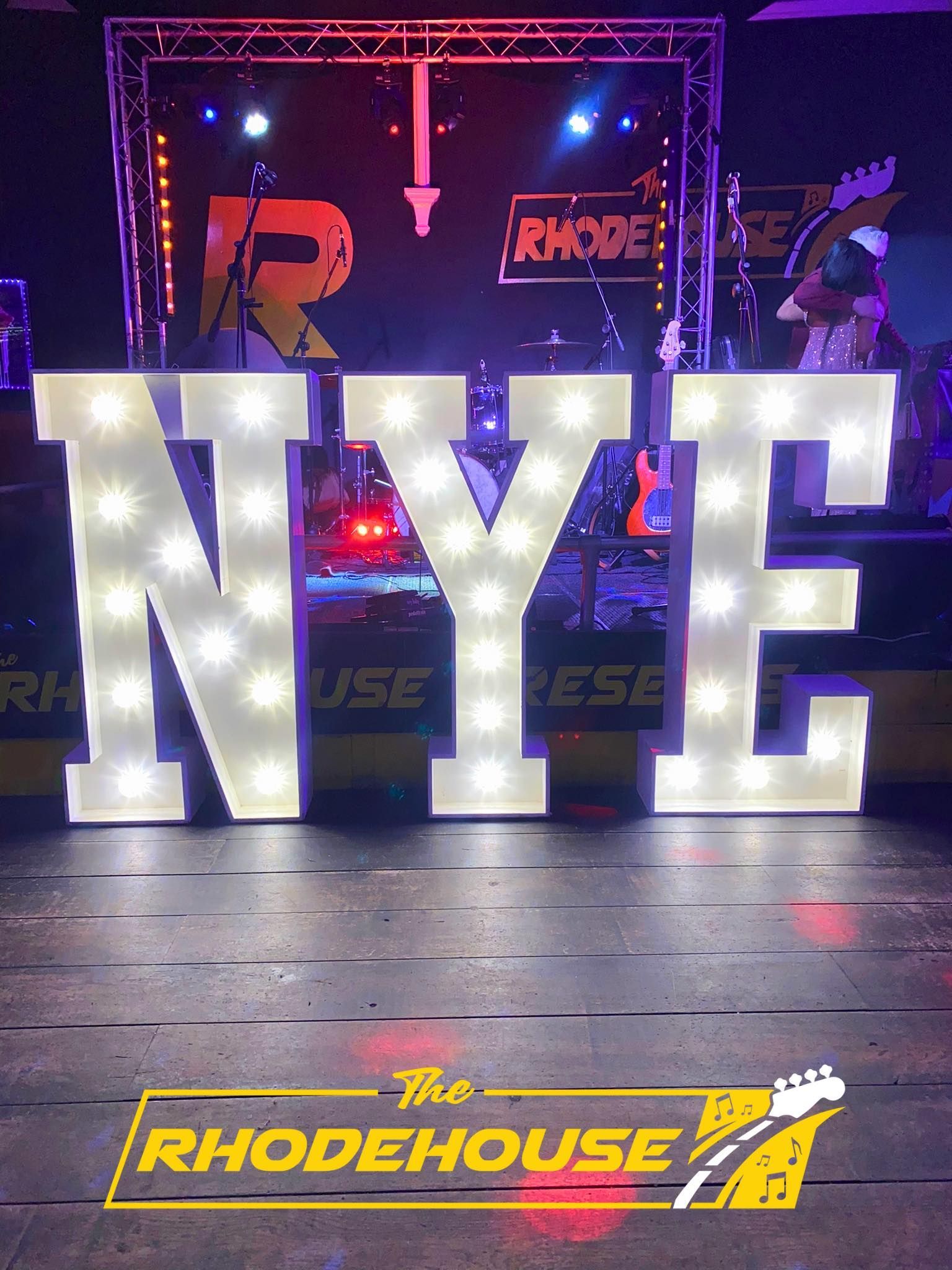 The word nyc is lit up on a stage in front of a band
