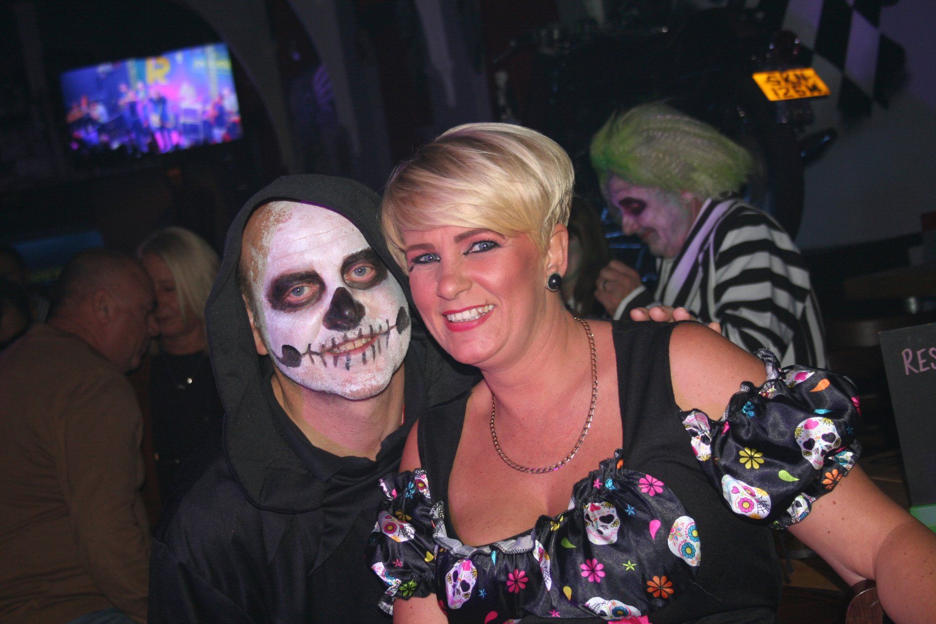 A man with a skeleton face paint is posing for a picture with a woman.