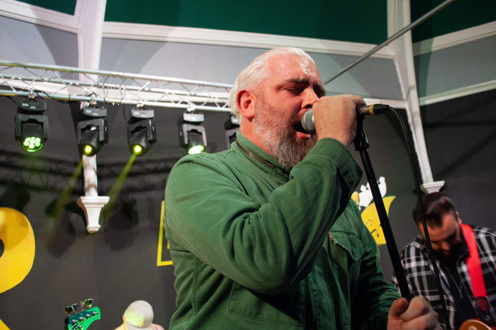 A man with a beard is singing into a microphone on a stage.