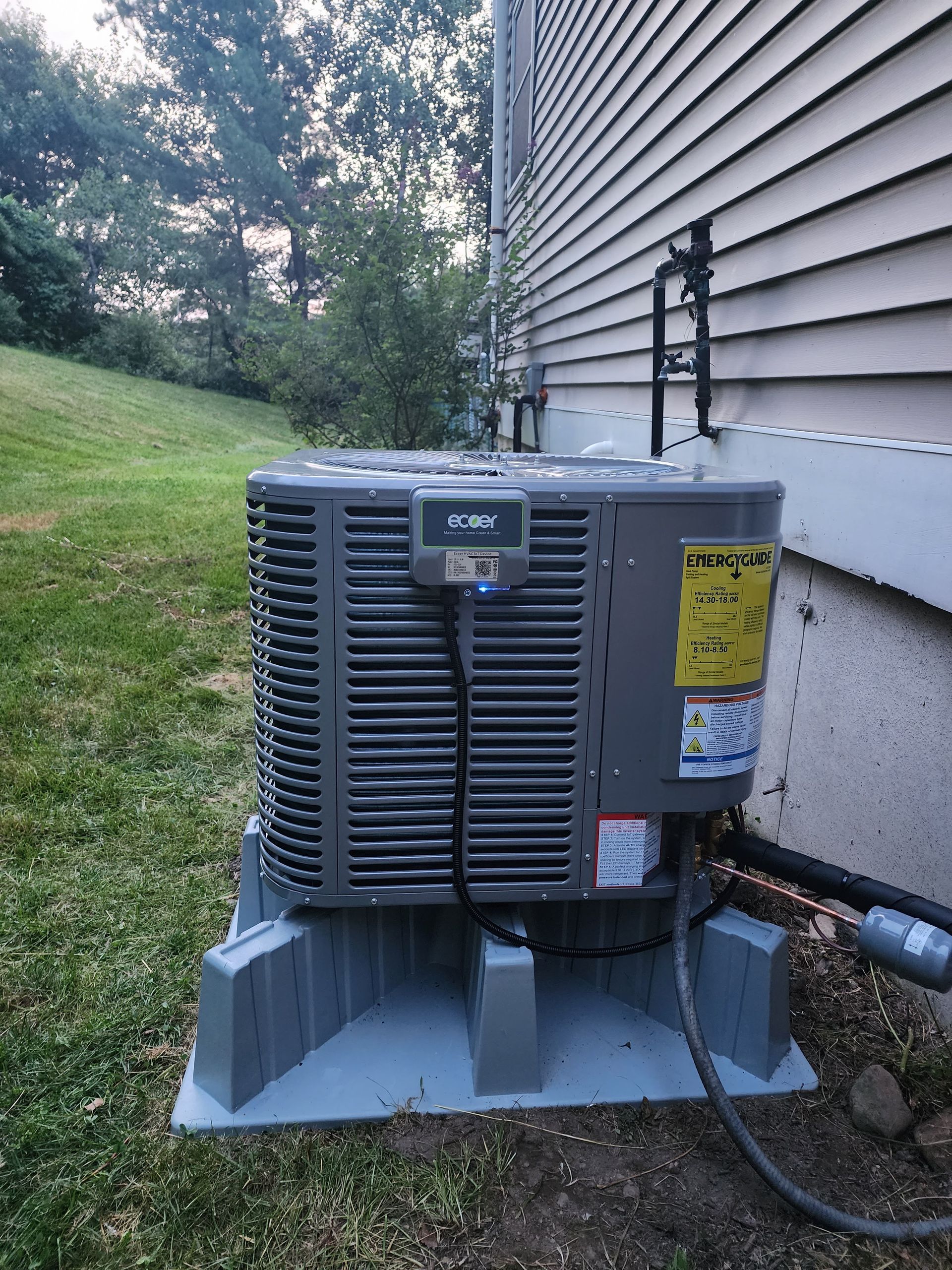 Air conditioning unit on a gray stand next to a light-colored house and green yard.