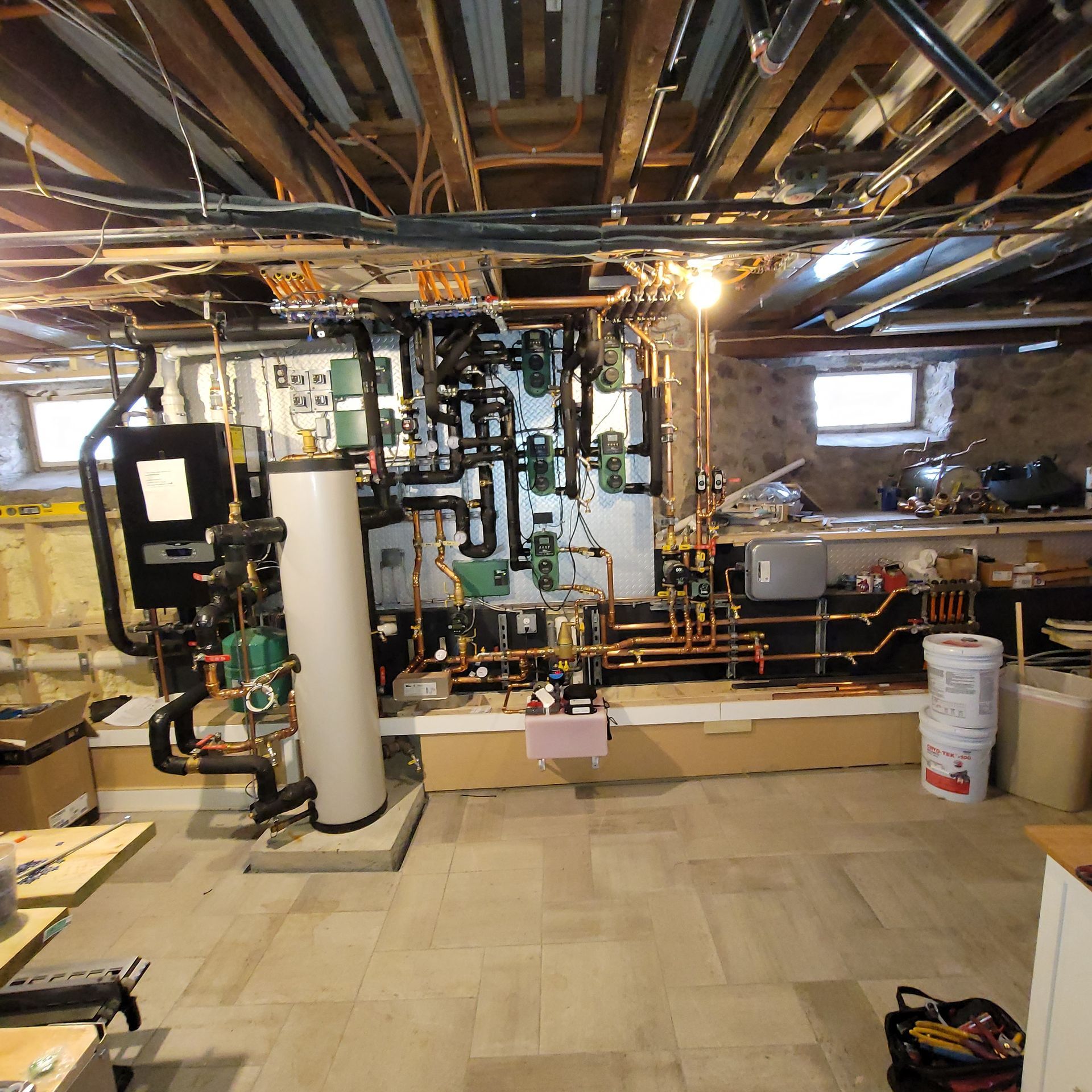 Basement with pipes, machinery, and a water heater, likely a utility room.