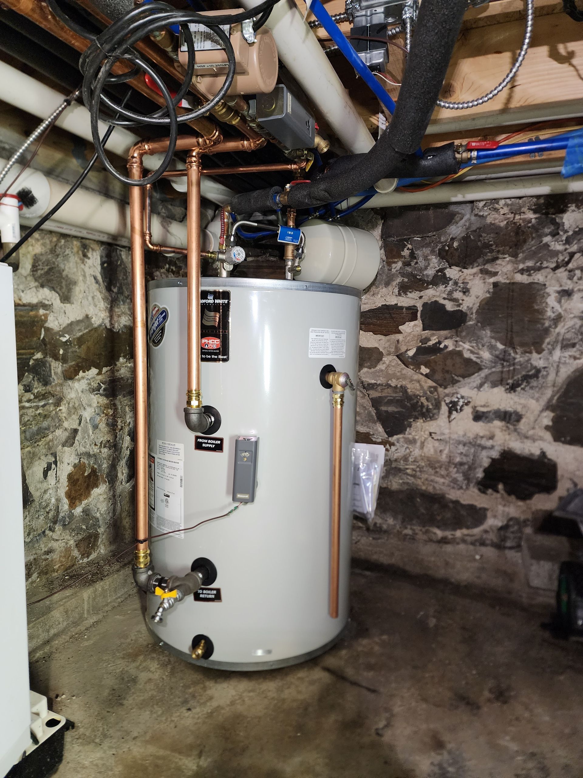 Water heater in basement with copper pipes.
