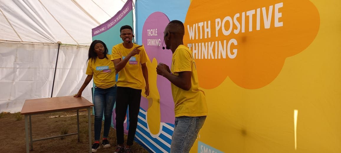 A group of people are dancing in front of a sesame street sign.