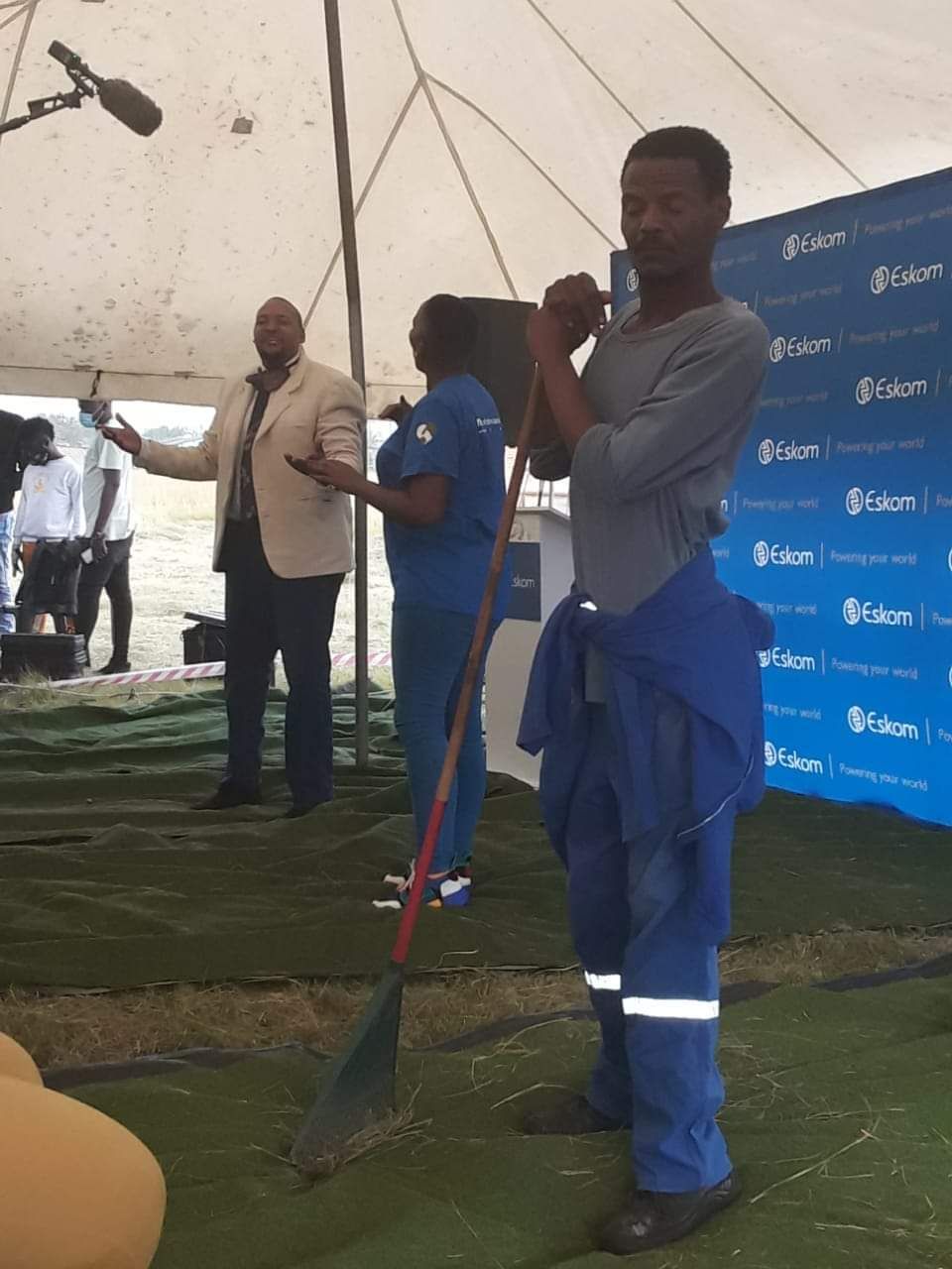 A man is holding a broom in front of a group of people