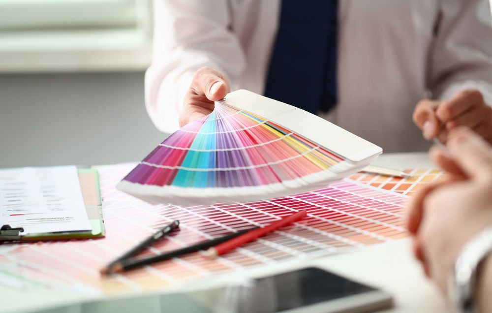 Man is Holding a Colour Palette in His Hands While Sitting at a Table — Classic Design & Print in Svensson Heights, QLD
