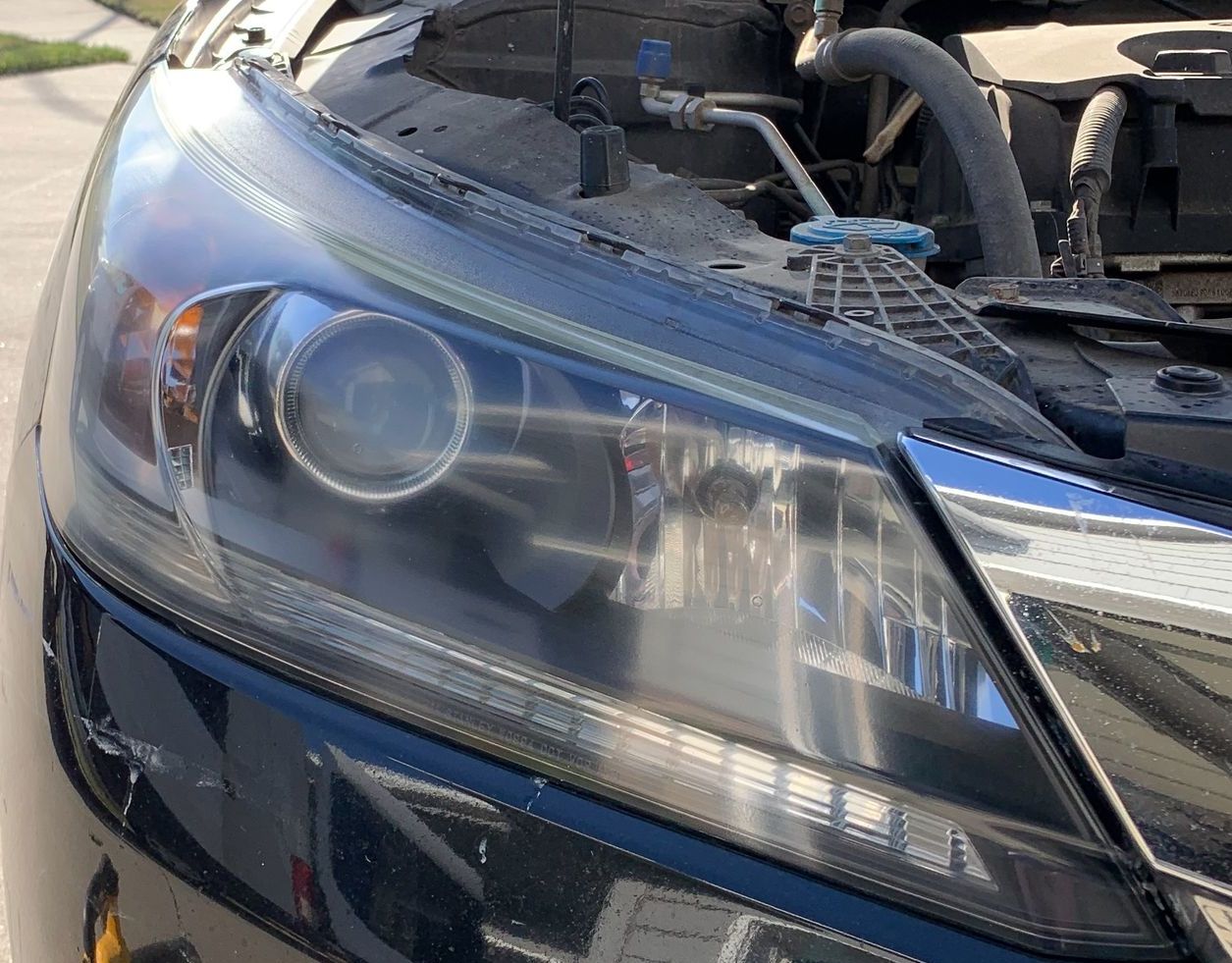 A close up of a car headlight with the hood open