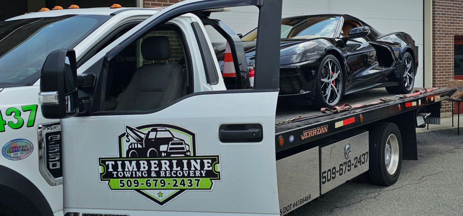A tow truck is carrying two cars on a trailer.